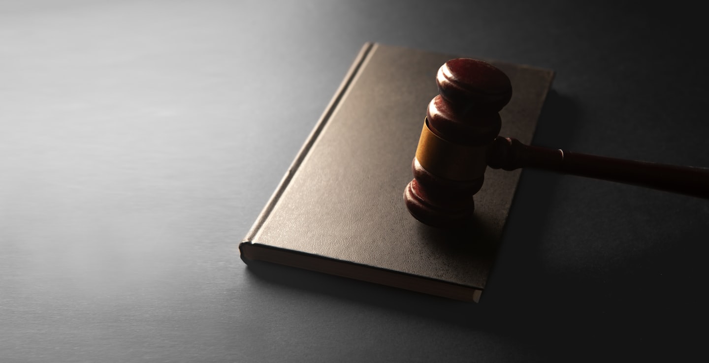 Wooden gavel rests on a closed legal book.