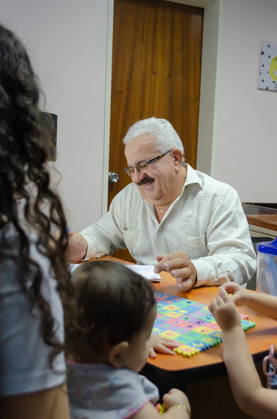 Man with glasses reviewing documents during a family desk meeting.