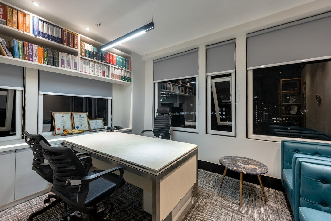 Modern office with desk chairs and bookshelves near windows.